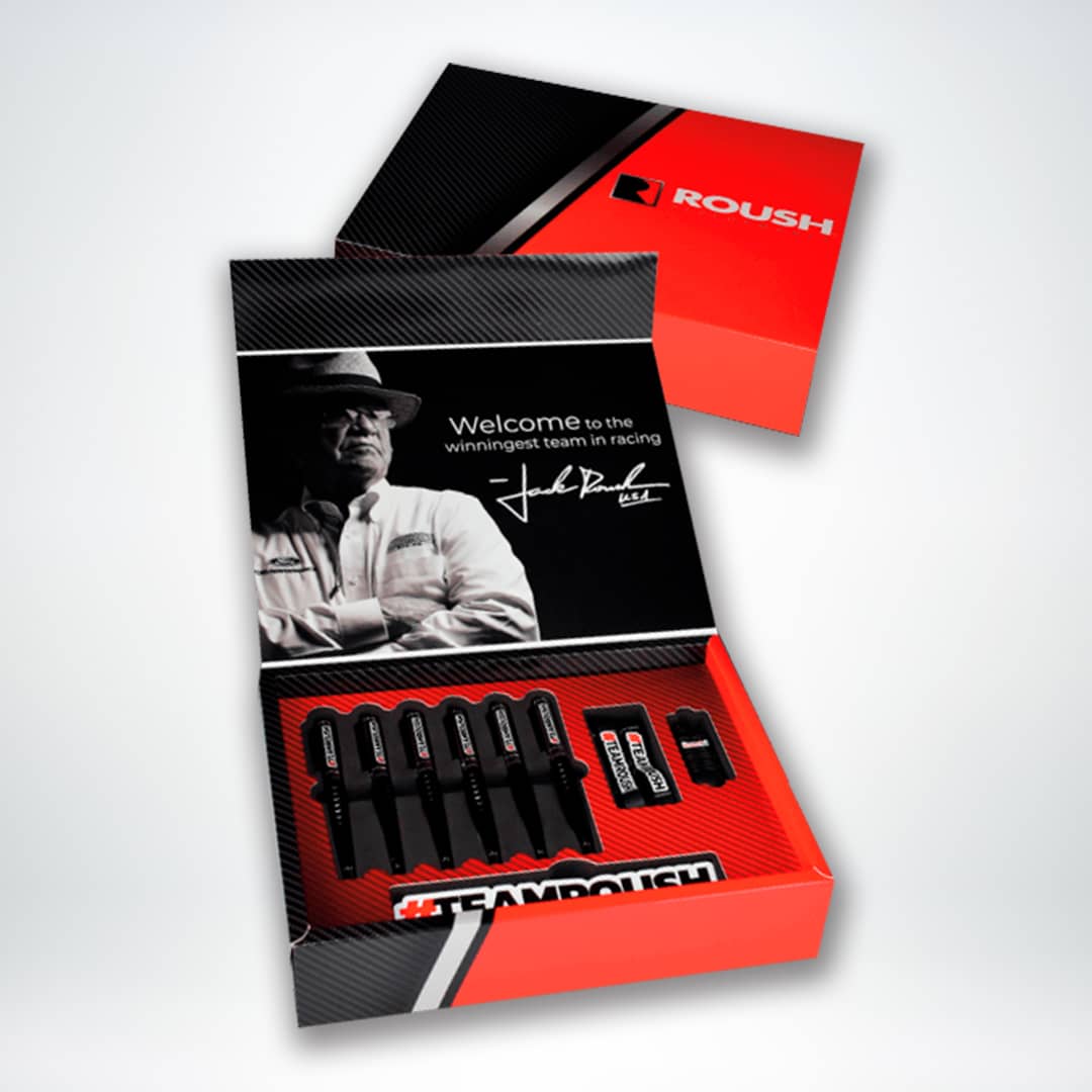 This image shows a brochure and box with Roush branding, featuring a black and red color scheme and an image of a person in a hat, welcoming to a team.
