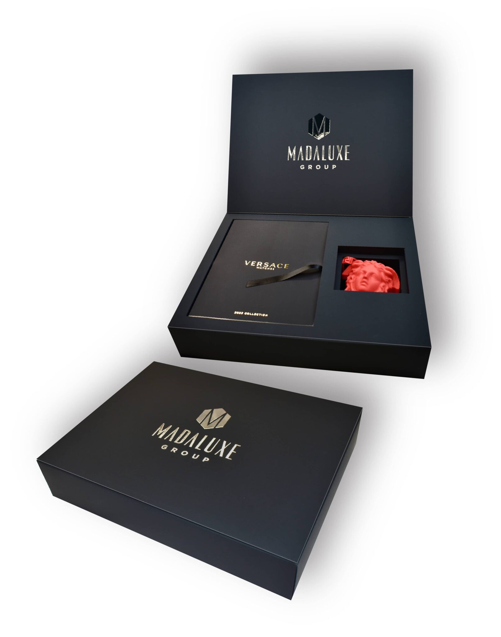 An open luxury gift box with the "MadaLuxe Group" logo, containing a Versace-branded item and a red, textured fabric, alongside a closed box.