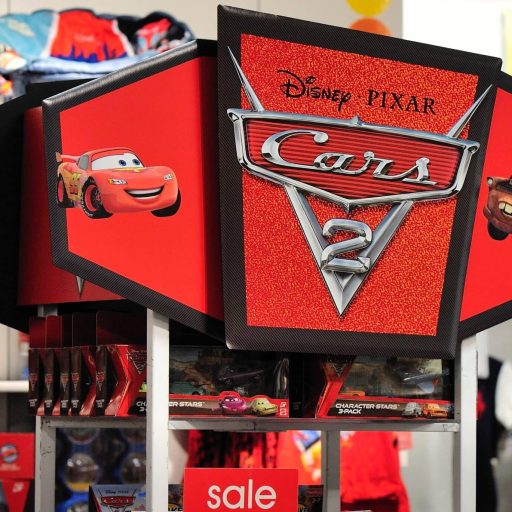 A large, red display for Disney Pixar's "Cars 2" with Lightning McQueen and Mater depicted. Merchandise is on sale under the vividly colored signage.